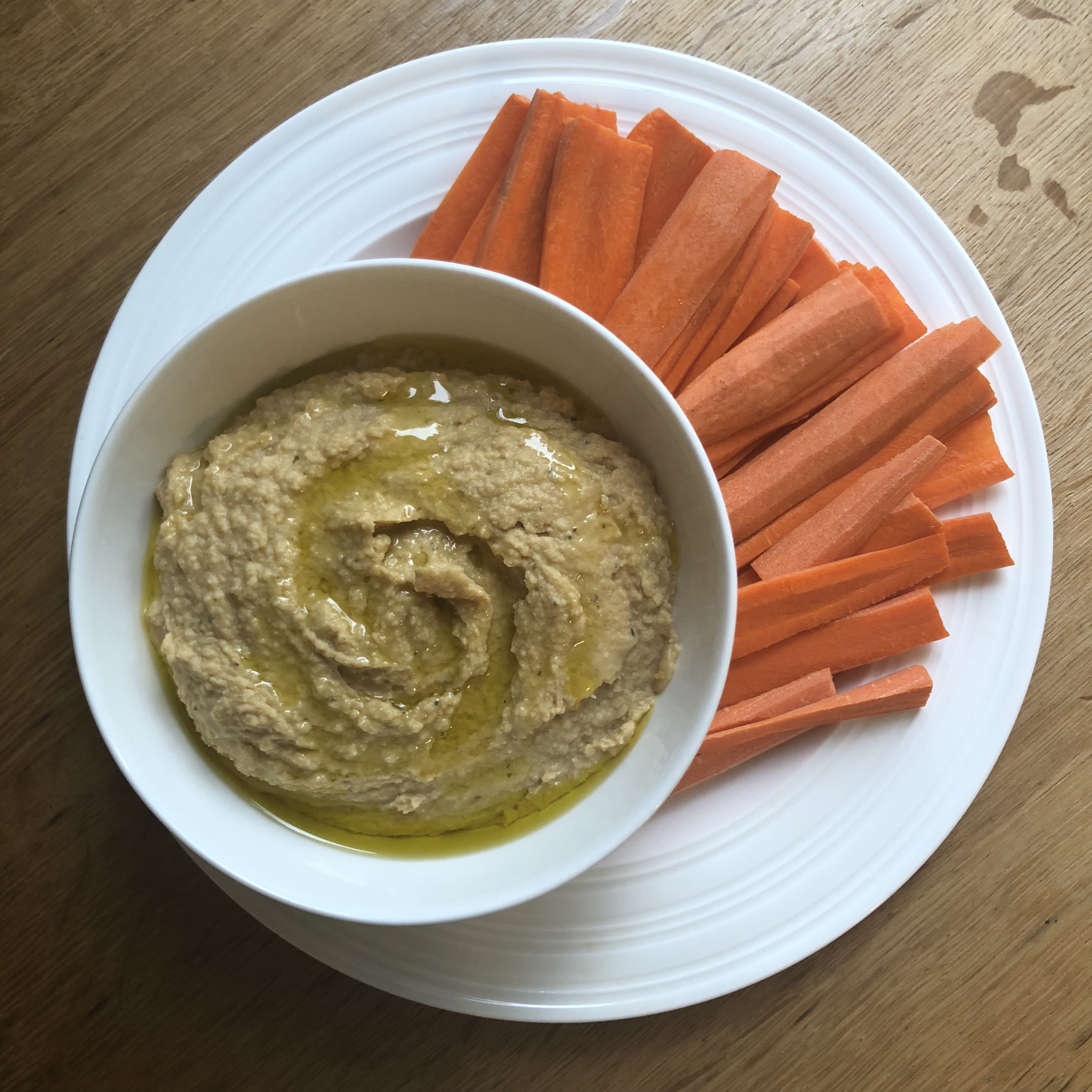 cultured chickpea hummus with olive oil on top and carrot sticks on the side